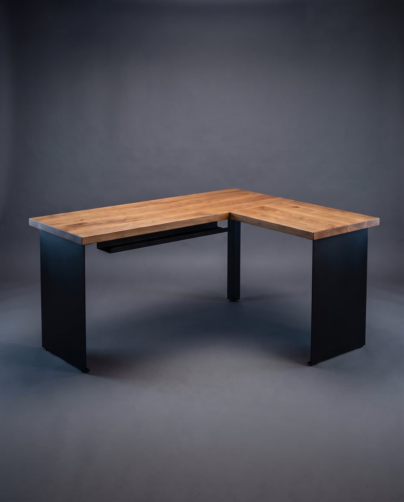 Bureau d'angle en L en chêne massif huilé sur piètement en acier noir, sur fond anthracite