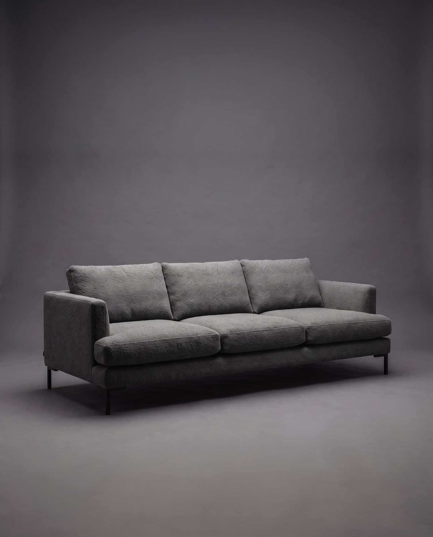 Canapé trois places bas et profond en tissu gris graphite sur pieds en métal noir, sur fond anthracite