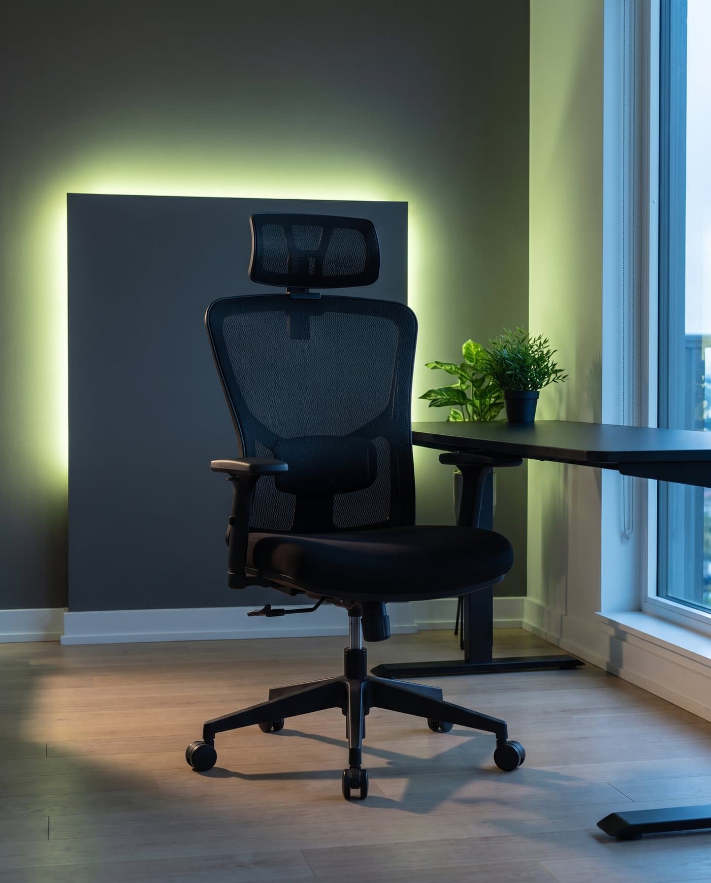 La chaise Quest devant un bureau noir, un néon vert lime diffus sur le mur