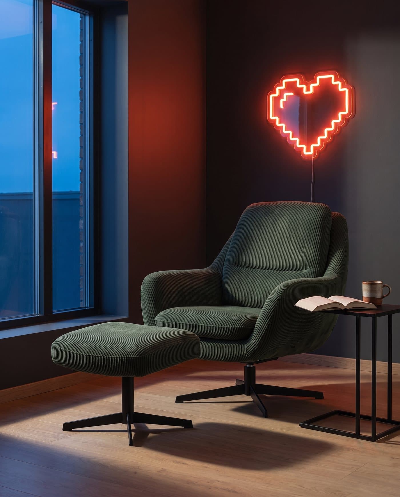 Le fauteuil Respawn et son ottoman près d'une grande fenêtre, un néon cœur rouge sur le mur
